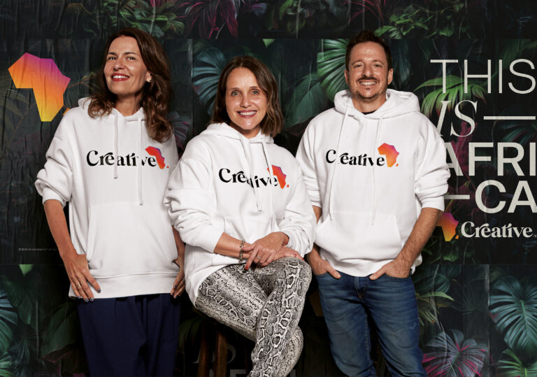 os Co-CCOs Joanna Monteiro, Mariana Sá e Nicholas Bergantin usando um moletom branco com o símbolo da Africa