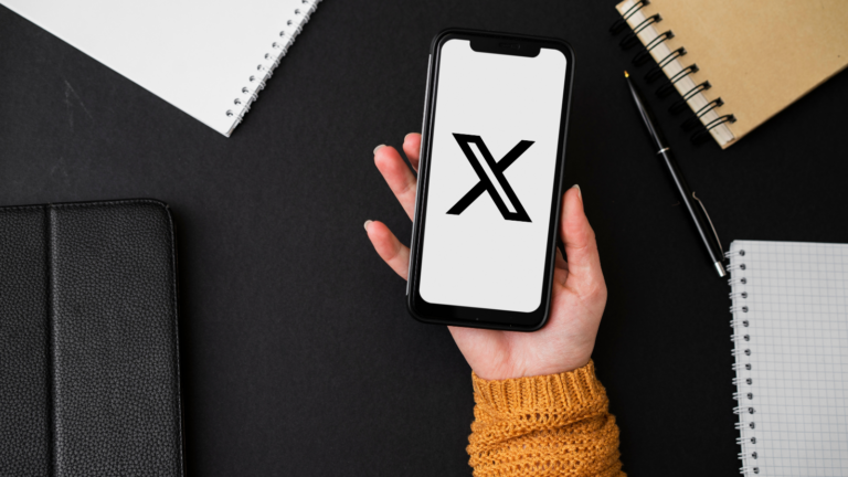 pessoa segurando um celular com a tela branca e a logo do X, rede social que permite publicação de artigos